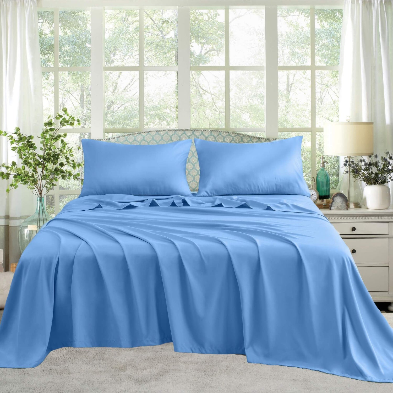 A neatly made bed with blue satin sheets and pillows