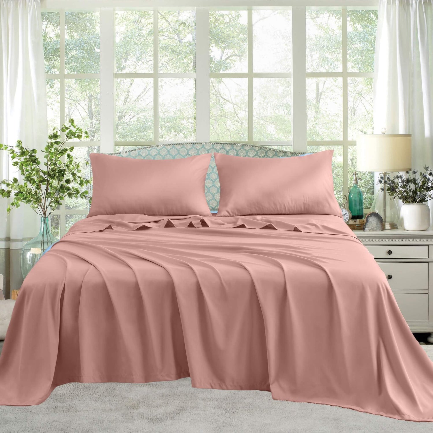 A neatly made bed with Pink satin sheets and pillows
